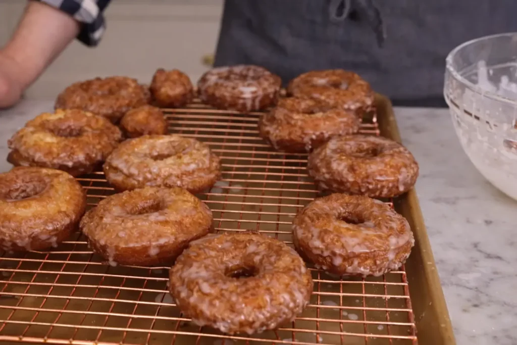 Crispy glazed sour cream donuts on wire rack after frying